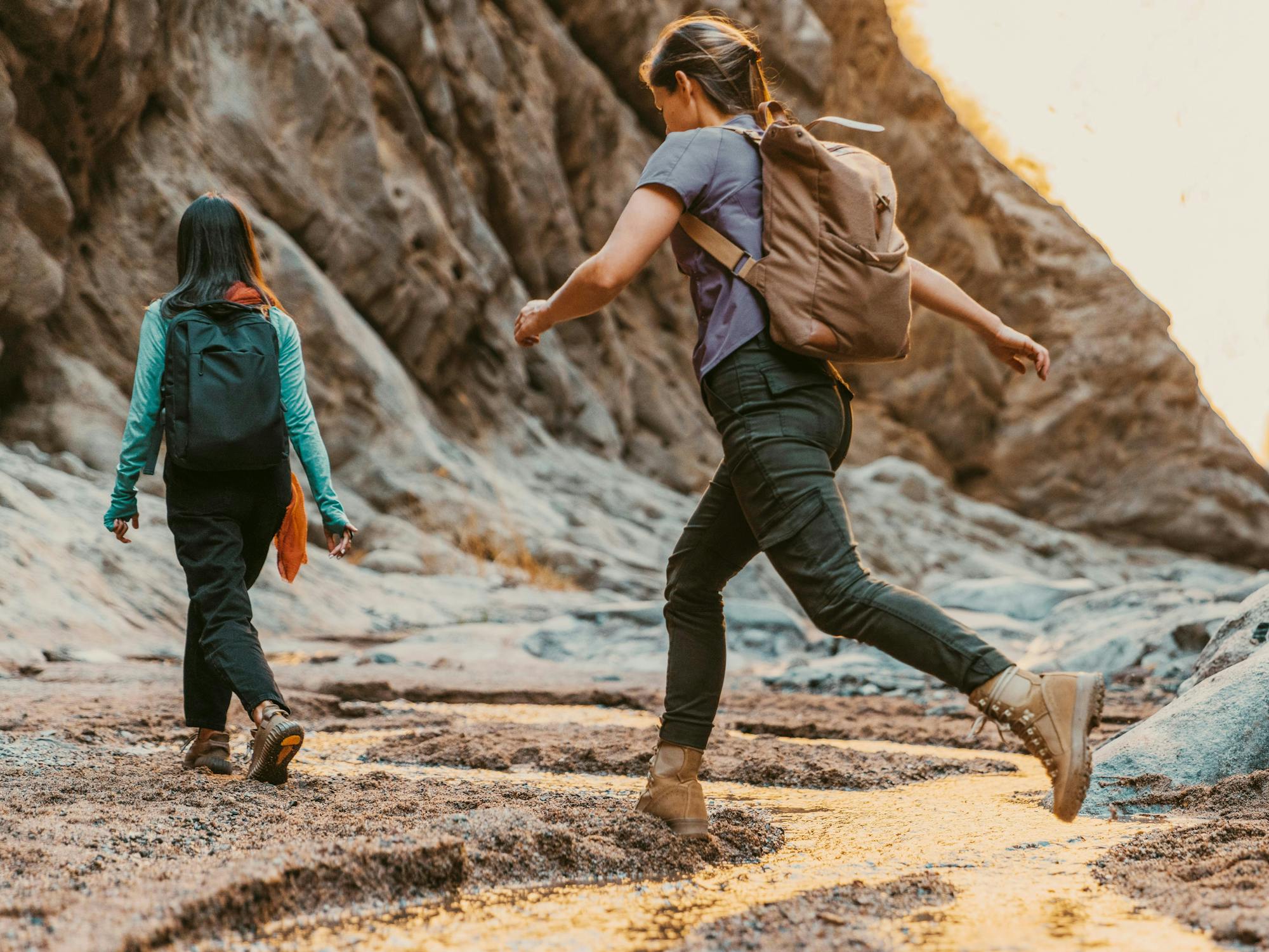 Two people hiking in a rocky terrain with a backpack.