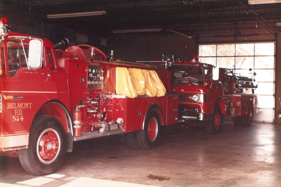 Red fire trucks parked inside a fire station garage.