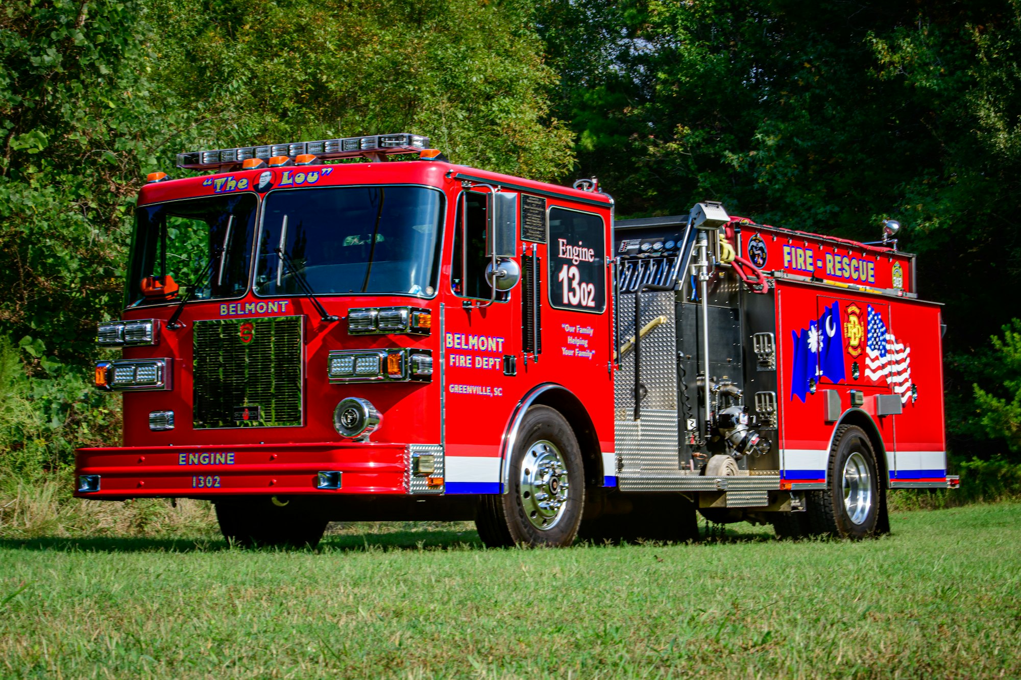 Red fire truck labeled "Engine 1302" from Belmont Fire Dept., parked on grass.
