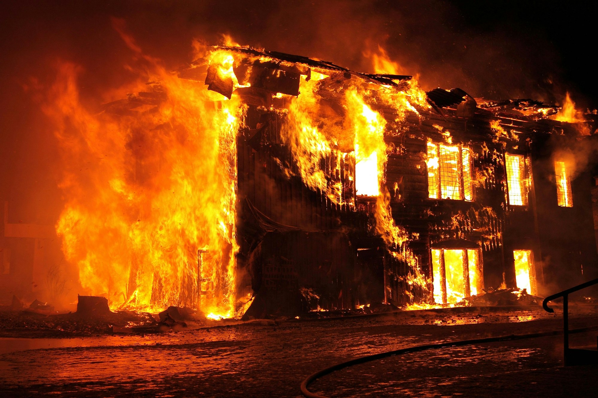 A building engulfed in flames at night with intense fire and smoke visible.