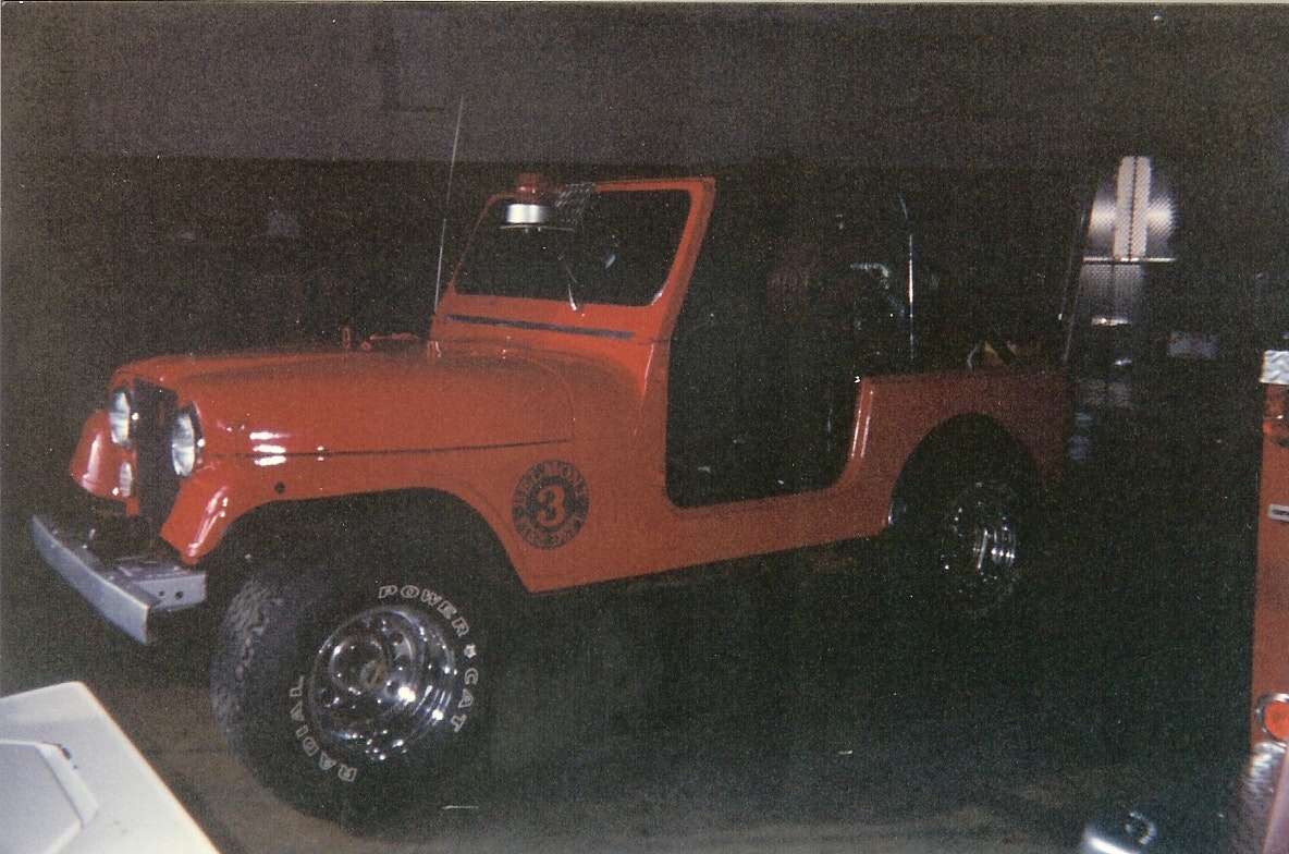 An orange fire department jeep with a siren and a "Brush 3" emblem on the side.