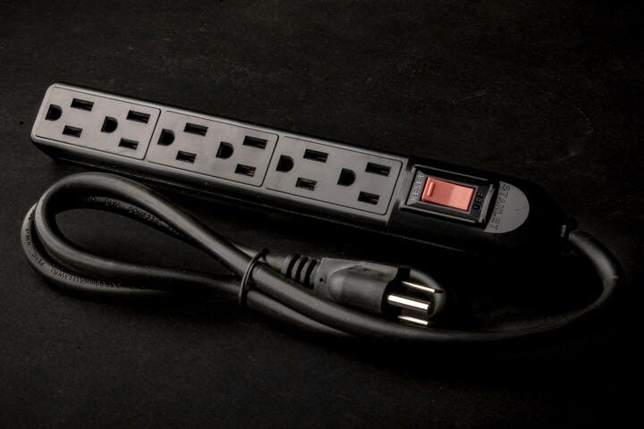 A power strip with multiple outlets and a red switch on a black background.