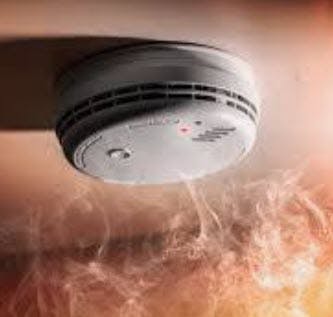 A smoke detector with smoke rising towards it.