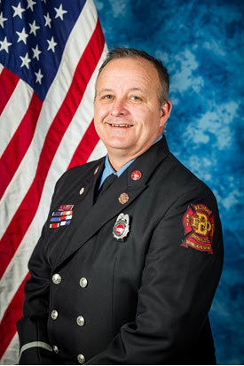 Lt Bob Neuer 2024 Photo stands in front of an American flag.