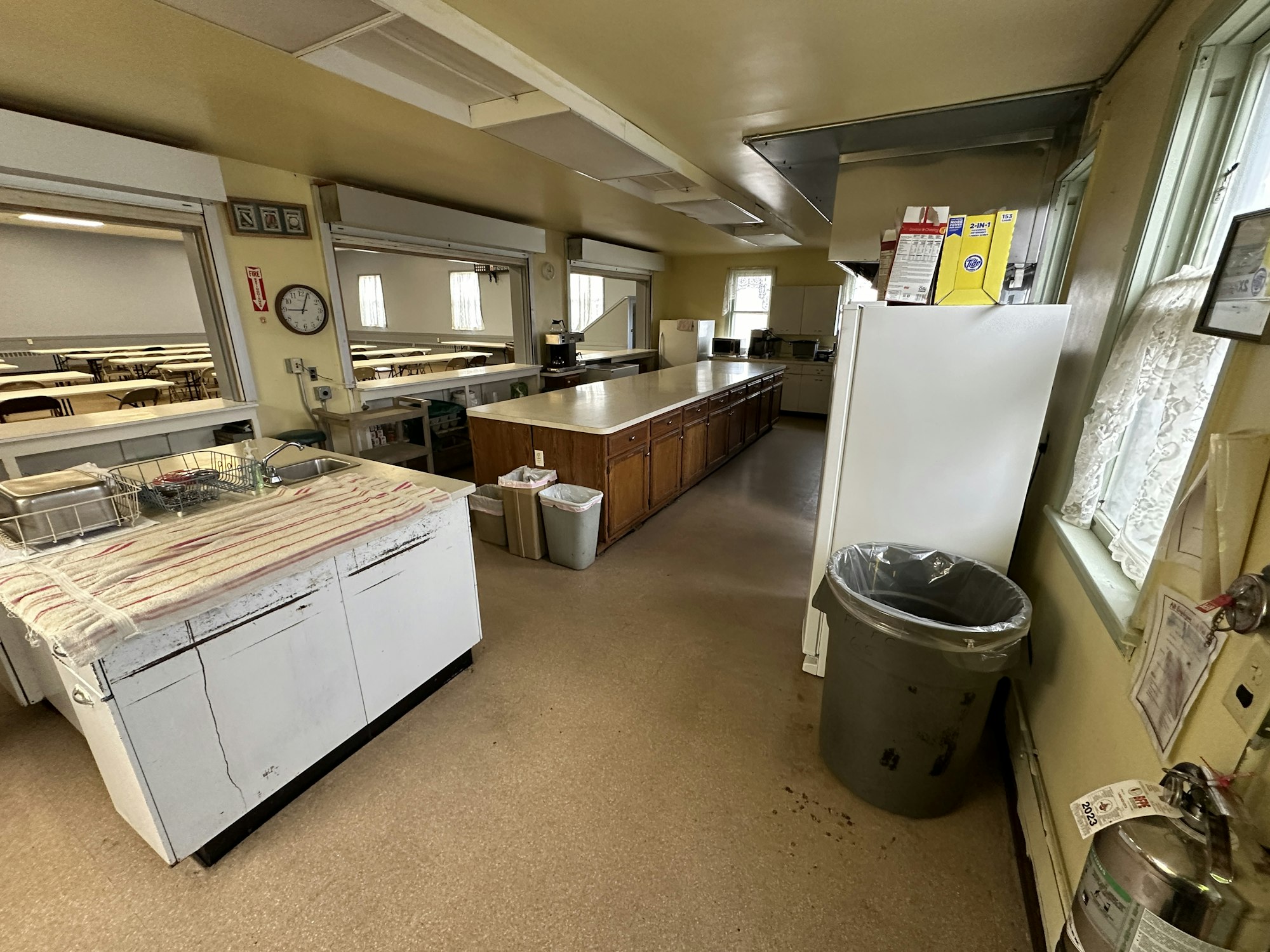 A commercial kitchen interior with equipment, counters, and tables.