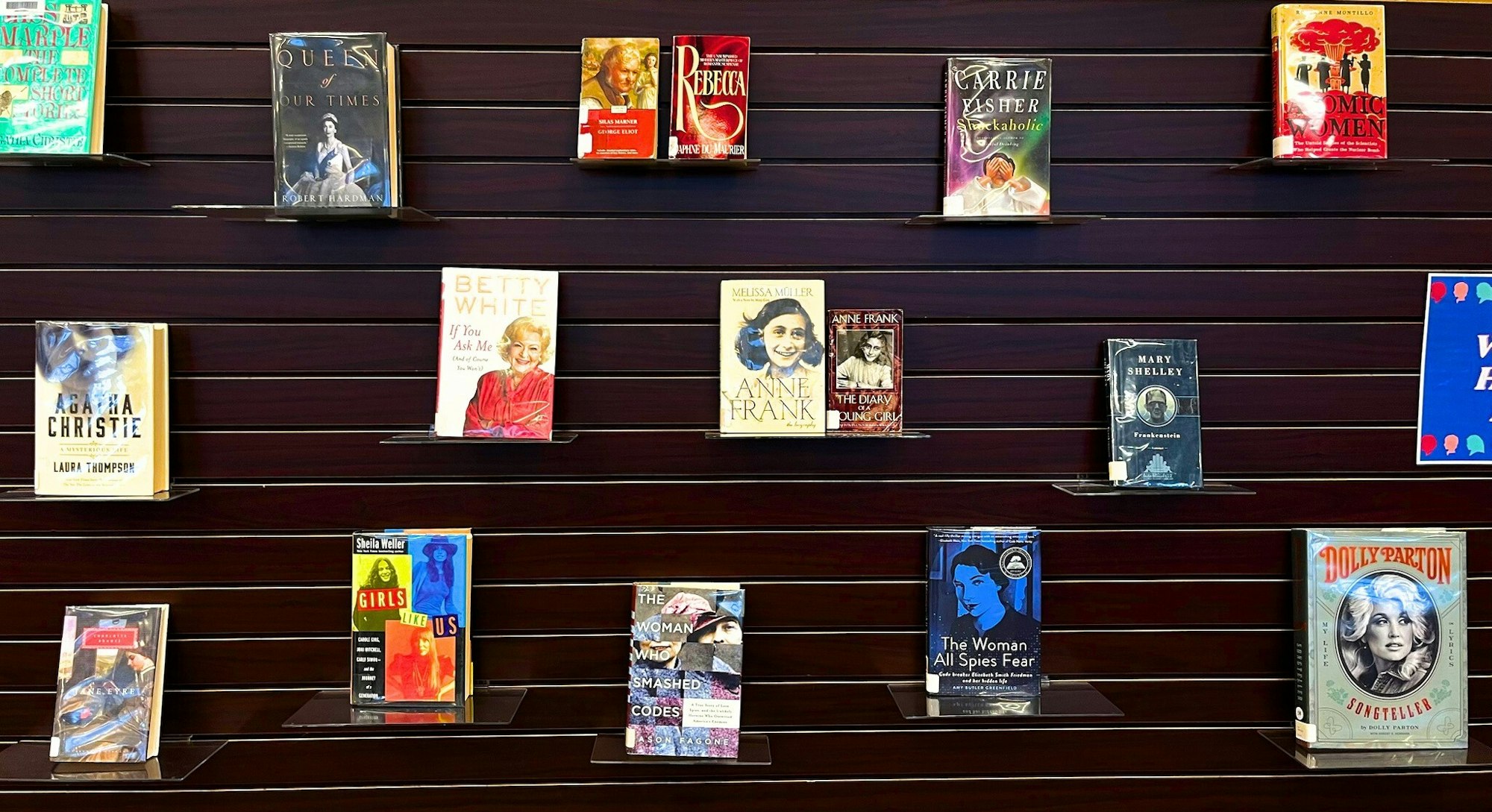 A display shelf with various books, featuring biographies, novels, and memoirs arranged neatly.