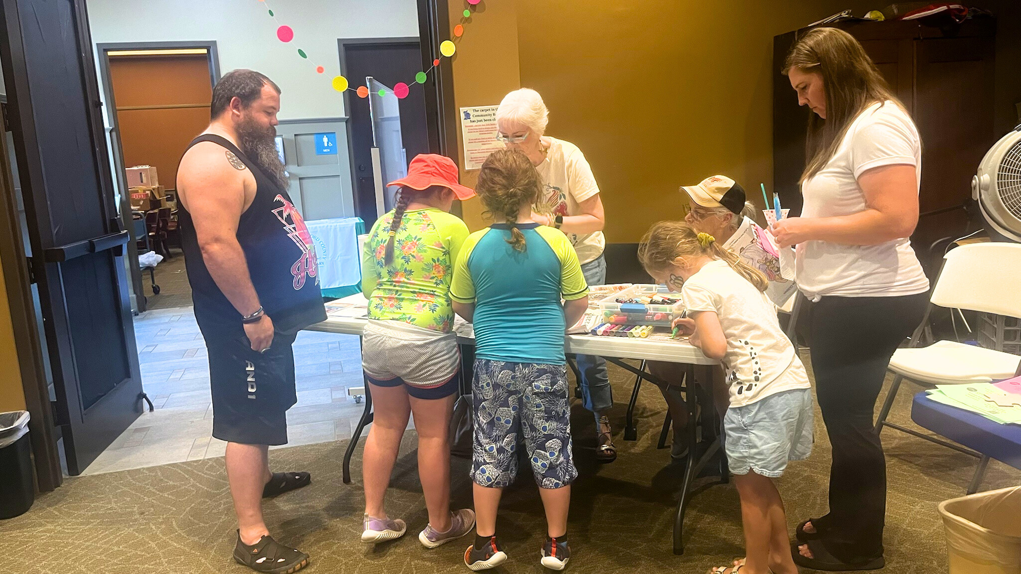 People gathered around a table engaged in arts and crafts in a room.