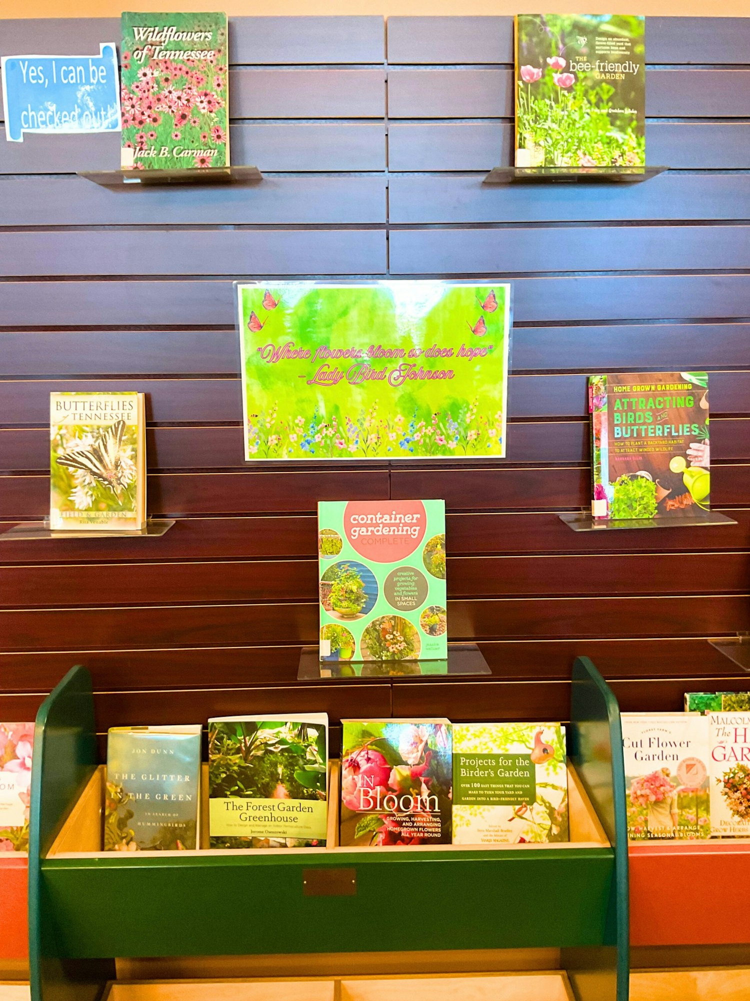 A display of gardening books, including topics on flowers, butterflies, and container gardening, with an inspirational quote.