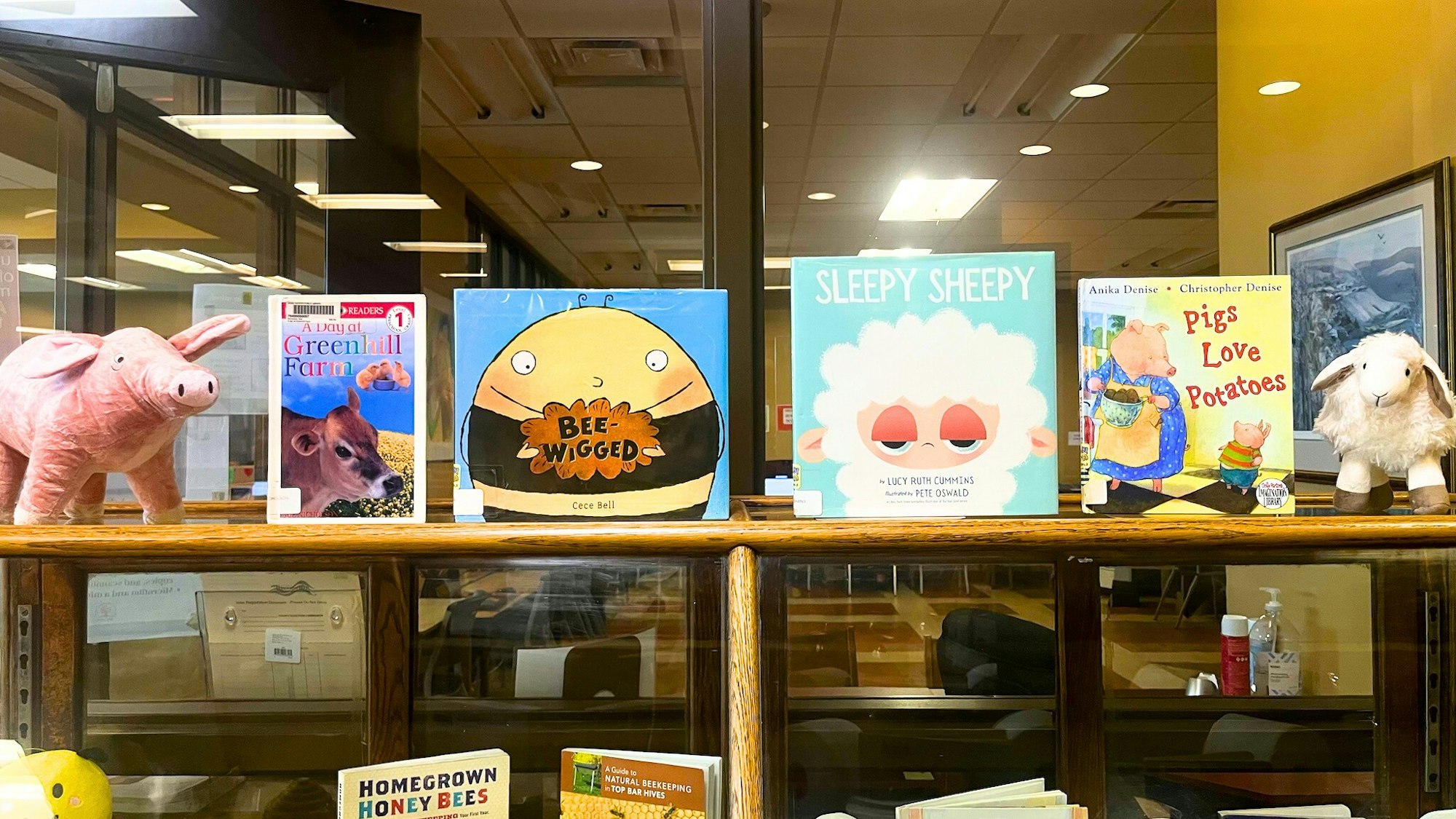 A display features children's books about farming, animals, and a goat plush toy, alongside a stuffed pig and sheep.