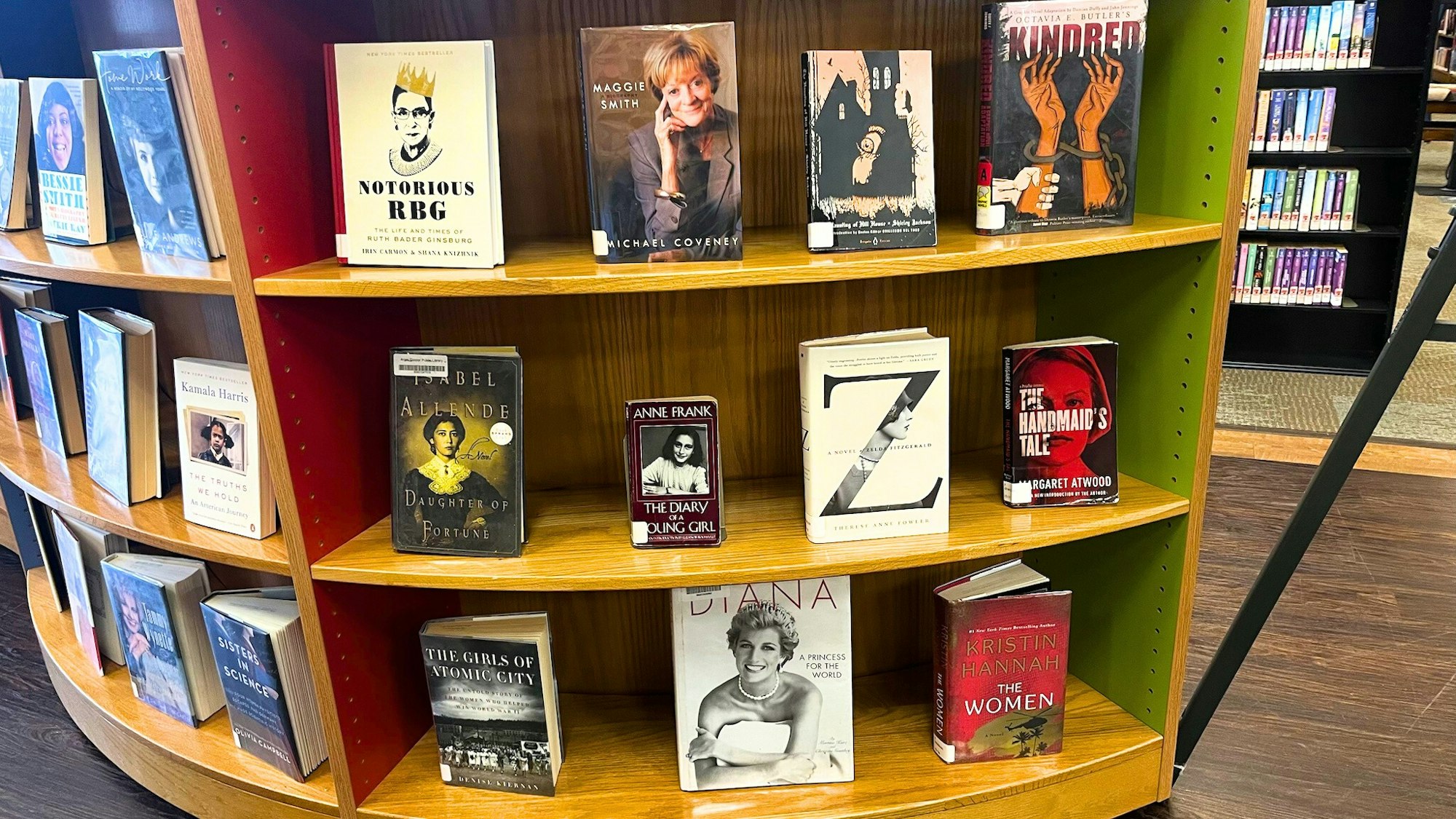 A library shelf featuring various notable books by and about influential women, including "Notorious RBG" and "The Handmaid's Tale."