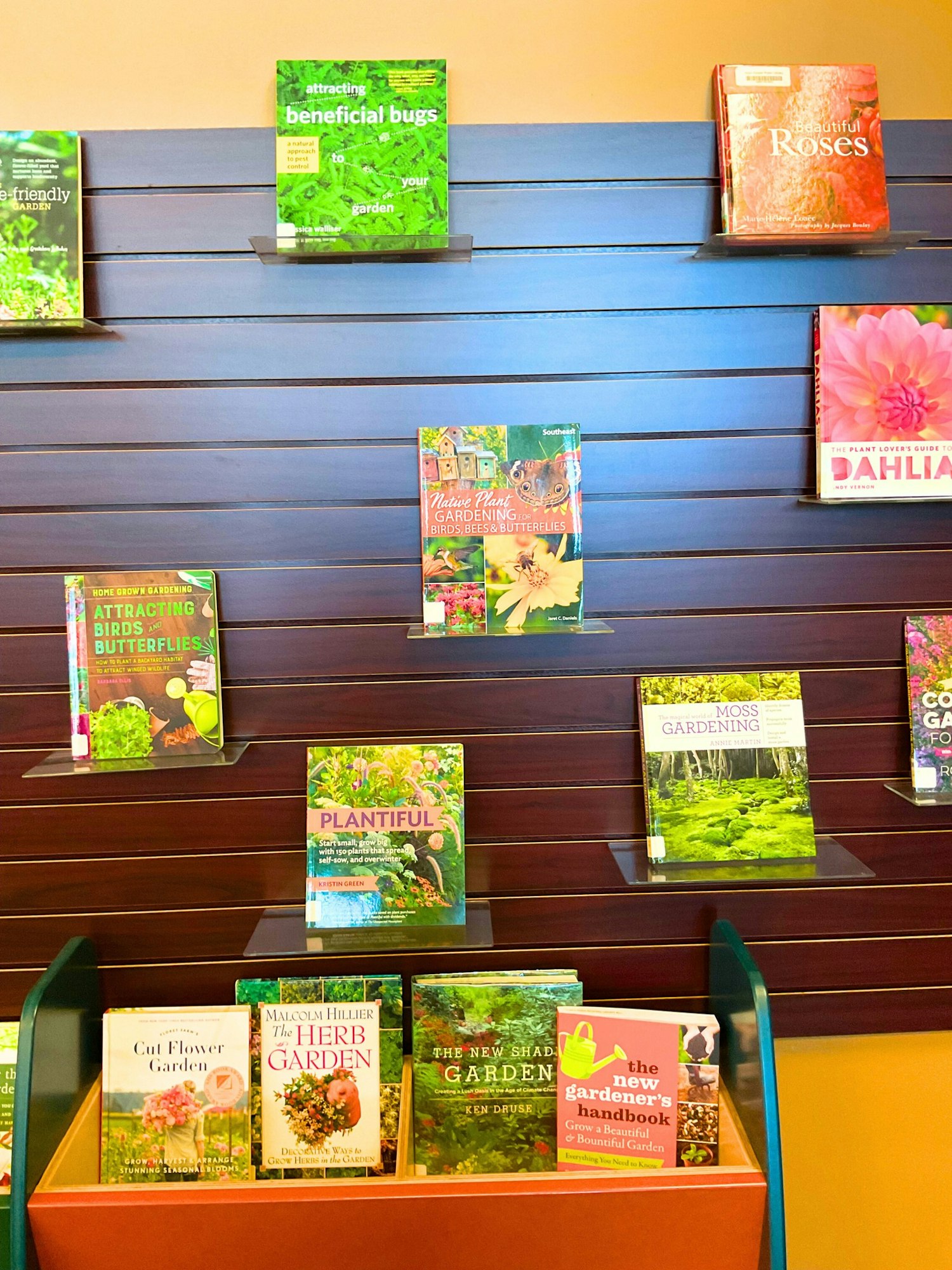 A display of gardening books covering topics like attracting beneficial bugs, native plants, and flower gardening.