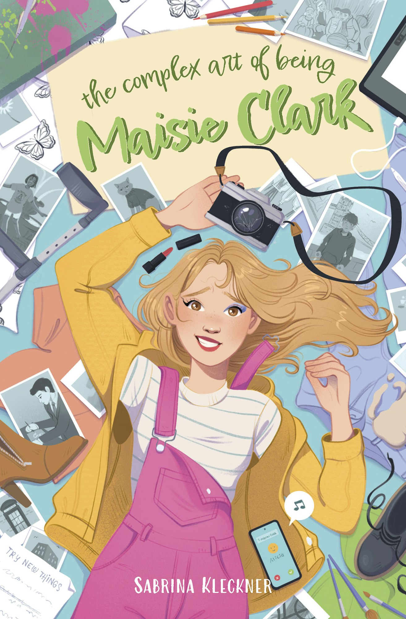 A girl with a camera lies among photos and art supplies, with "The Complex Art of Being Maisie Clark" written above.