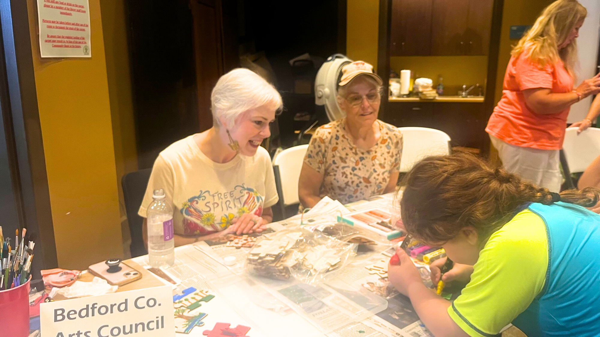 People at a table doing arts and crafts, with a sign reading "Bedford Co. Arts Council."