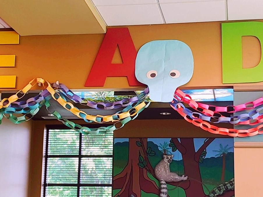 Colorful paper chains hung across a classroom with letters on the wall and a cartoon elephant cutout.