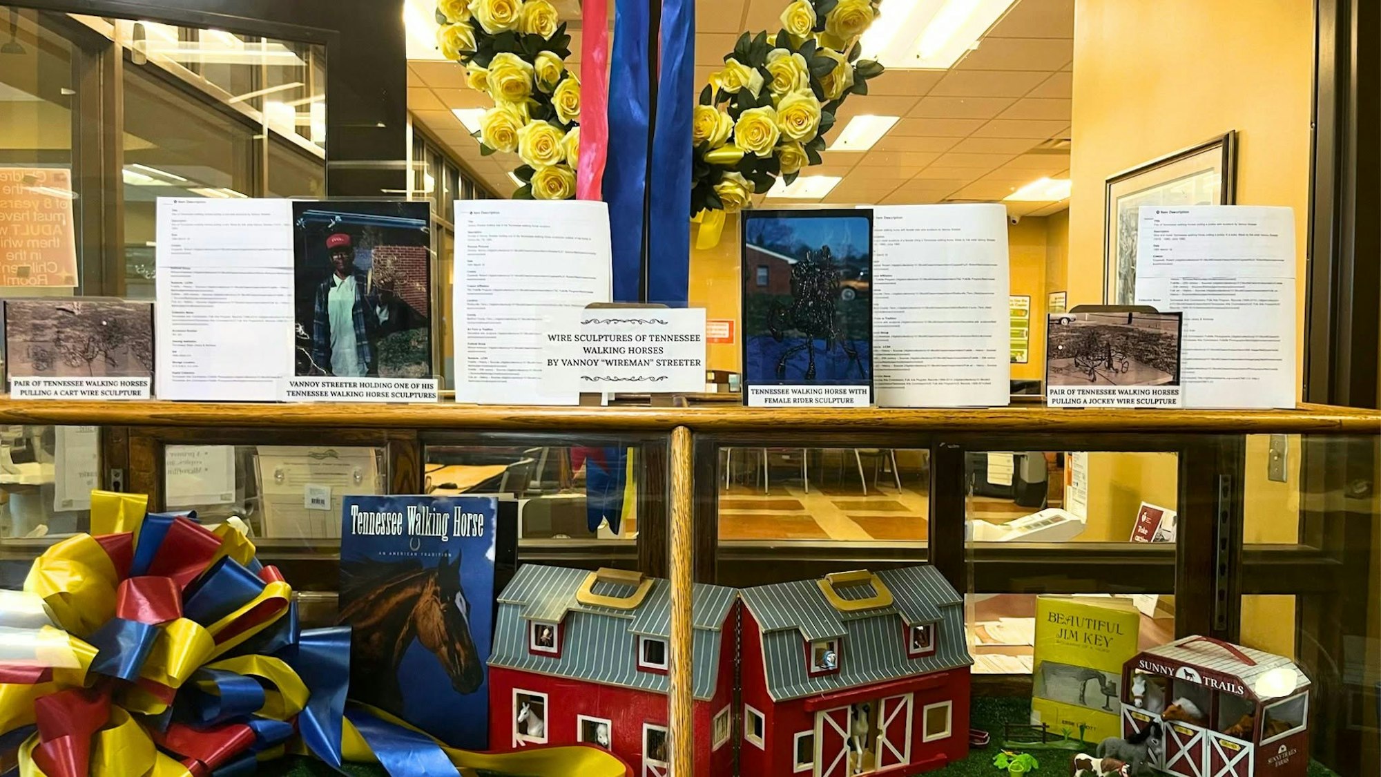 The image features an exhibit showcasing wire sculptures of Tennessee walking horses by Vannoy "Wireman" Streeter, with books and decorative elements.