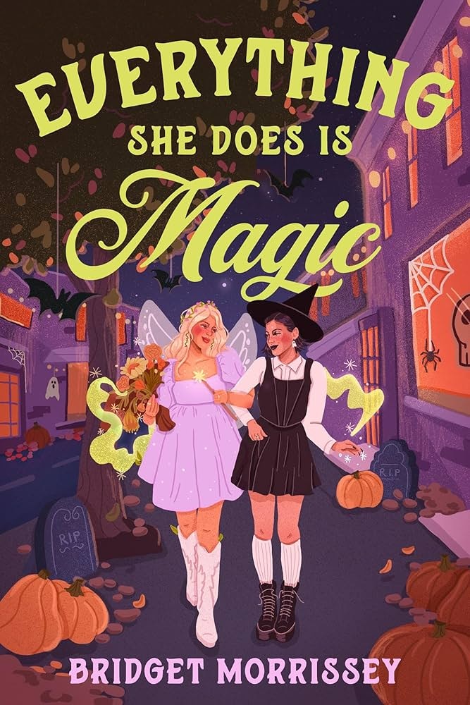 Two women, a fairy and a witch, walking in a decorated Halloween street with pumpkins and gravestones. Text: "Everything She Does Is Magic."