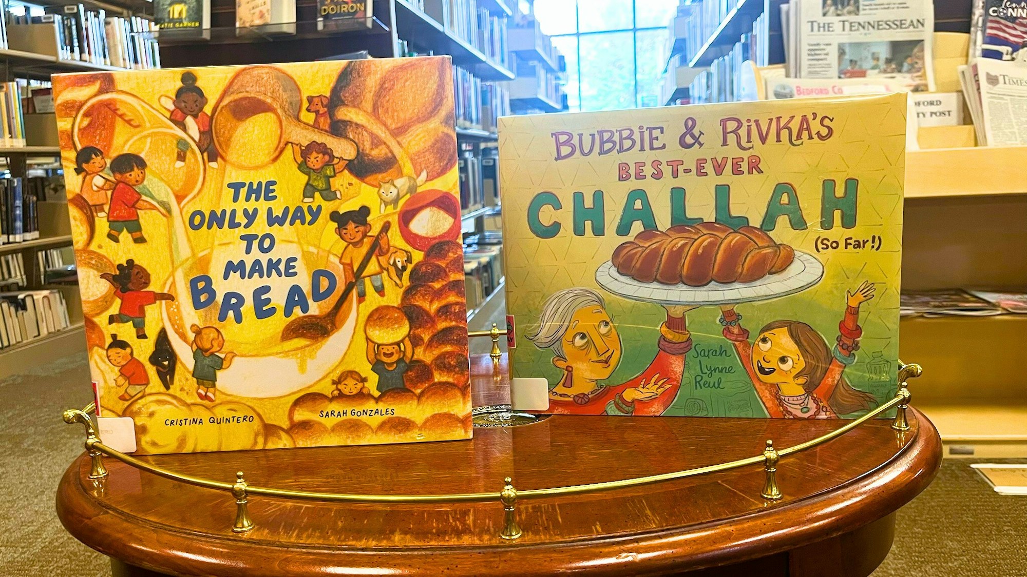 Two children's books on baking bread displayed on a library table.