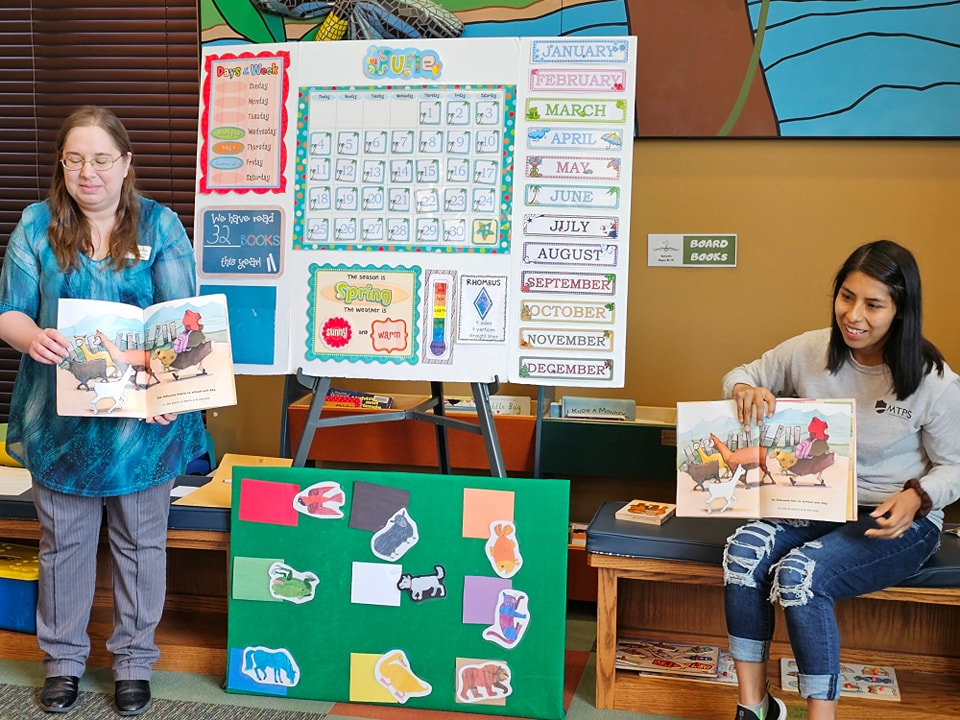 Two people presenting educational materials in a classroom setting.