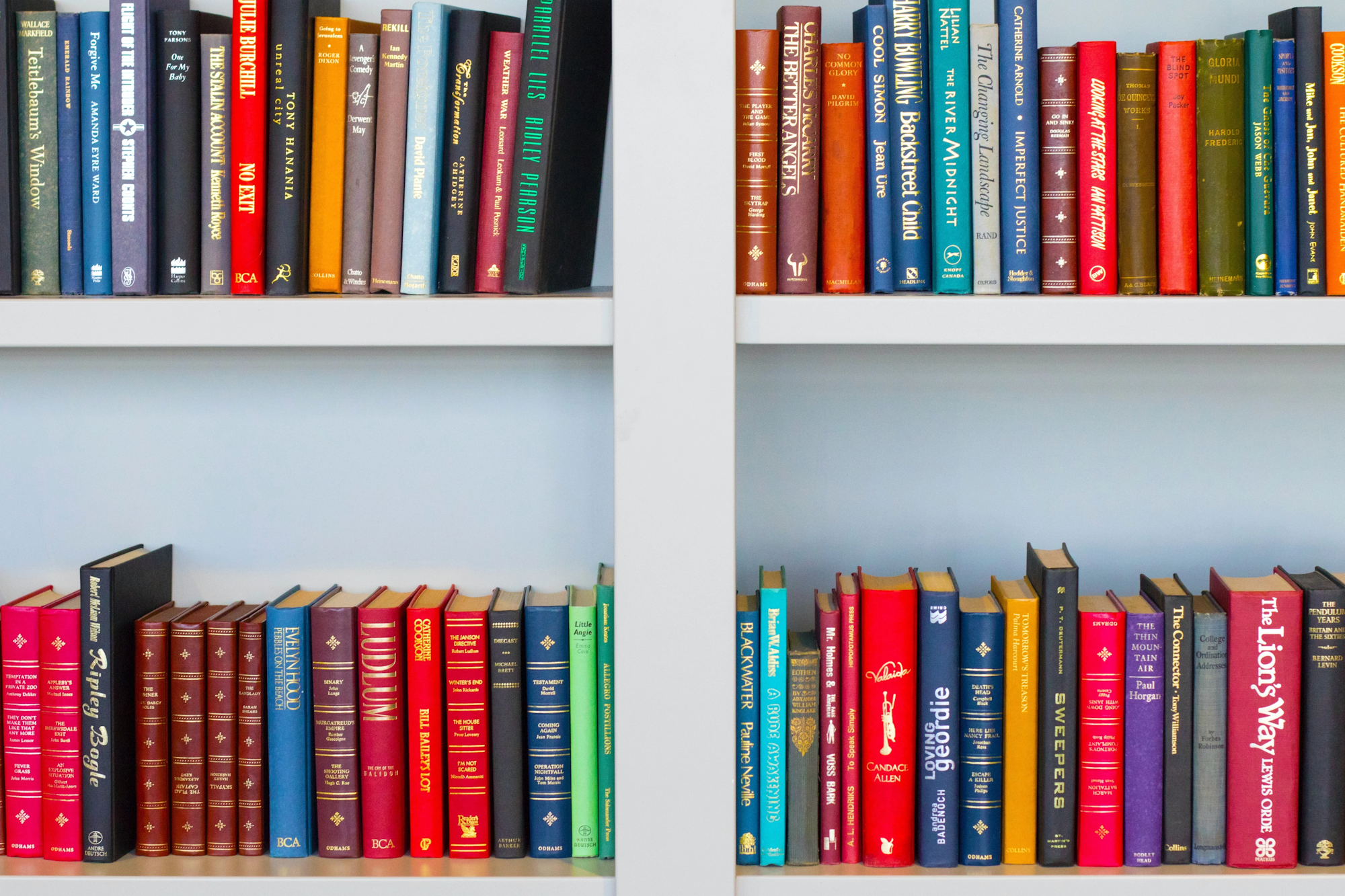 Two bookshelves filled with colorful hardcover books, neatly arranged.