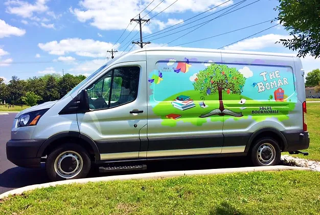 A colorful van with a tree, books, and the text "The Bomar", "STUDIO", and "BOOKMOBILE".