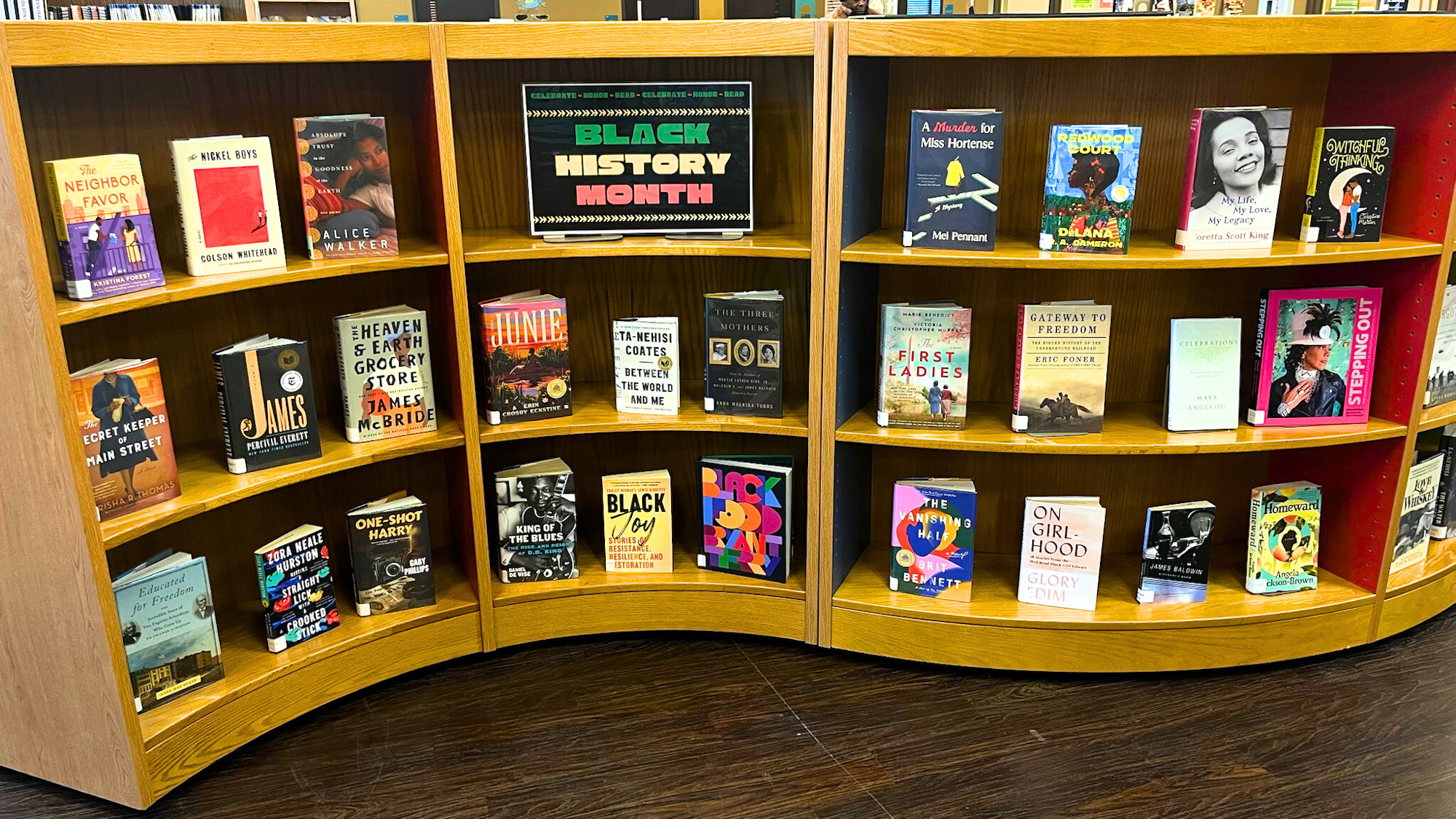 A display of books celebrating Black History Month, featuring notable authors and titles on a wooden bookshelf.