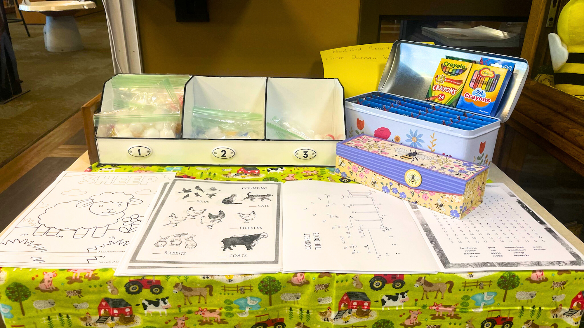 The image shows a colorful table with educational materials, including coloring pages, crayons, and activity sheets related to farm animals.