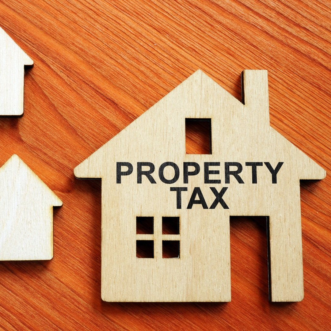 Wooden house cutout labeled "PROPERTY TAX" on a wooden background.
