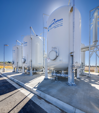 Large industrial storage tanks outdoors with pipes and valves, labeled "Carbon".