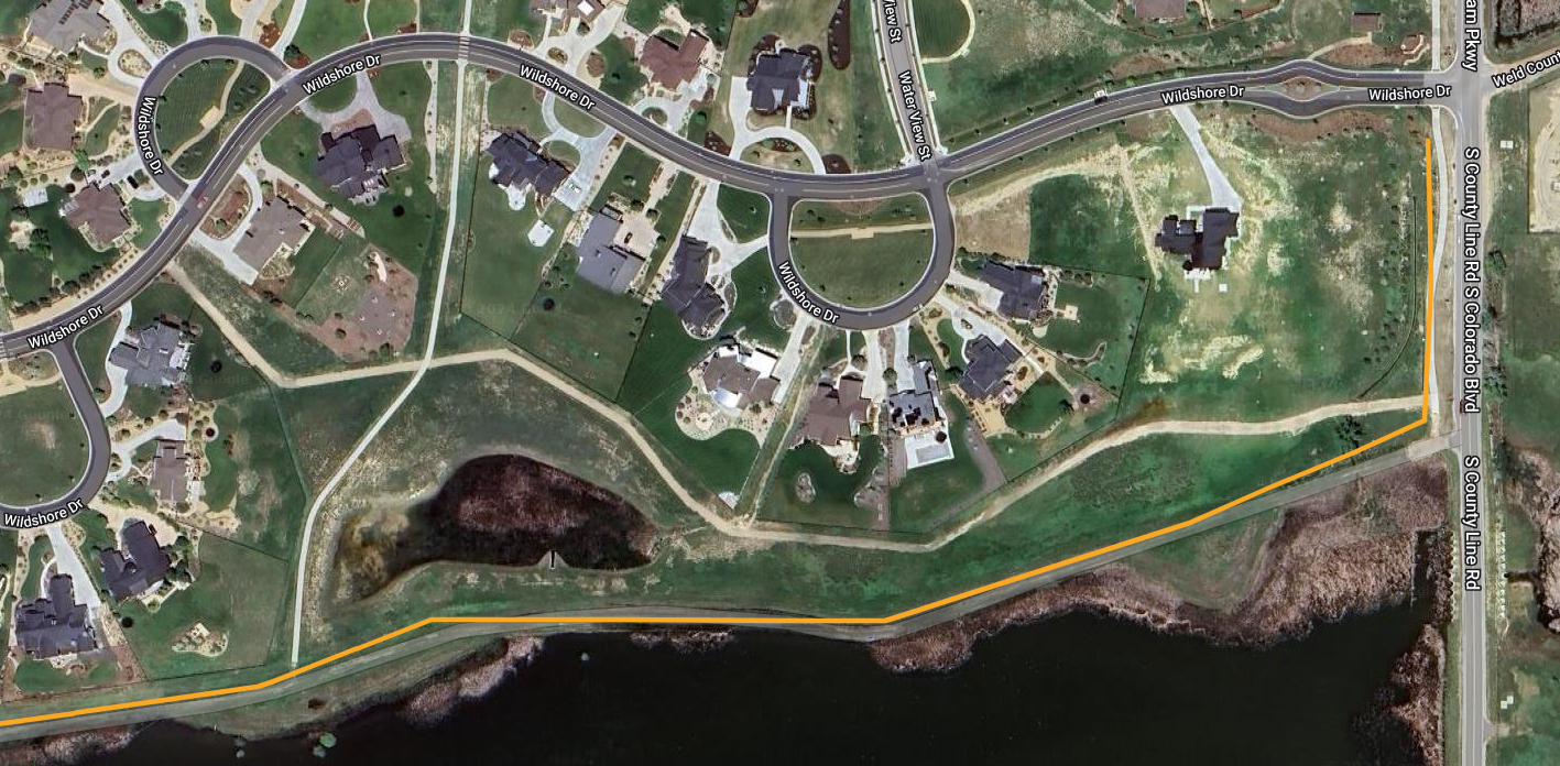Aerial view of a suburban area with houses, roads, and a body of water.