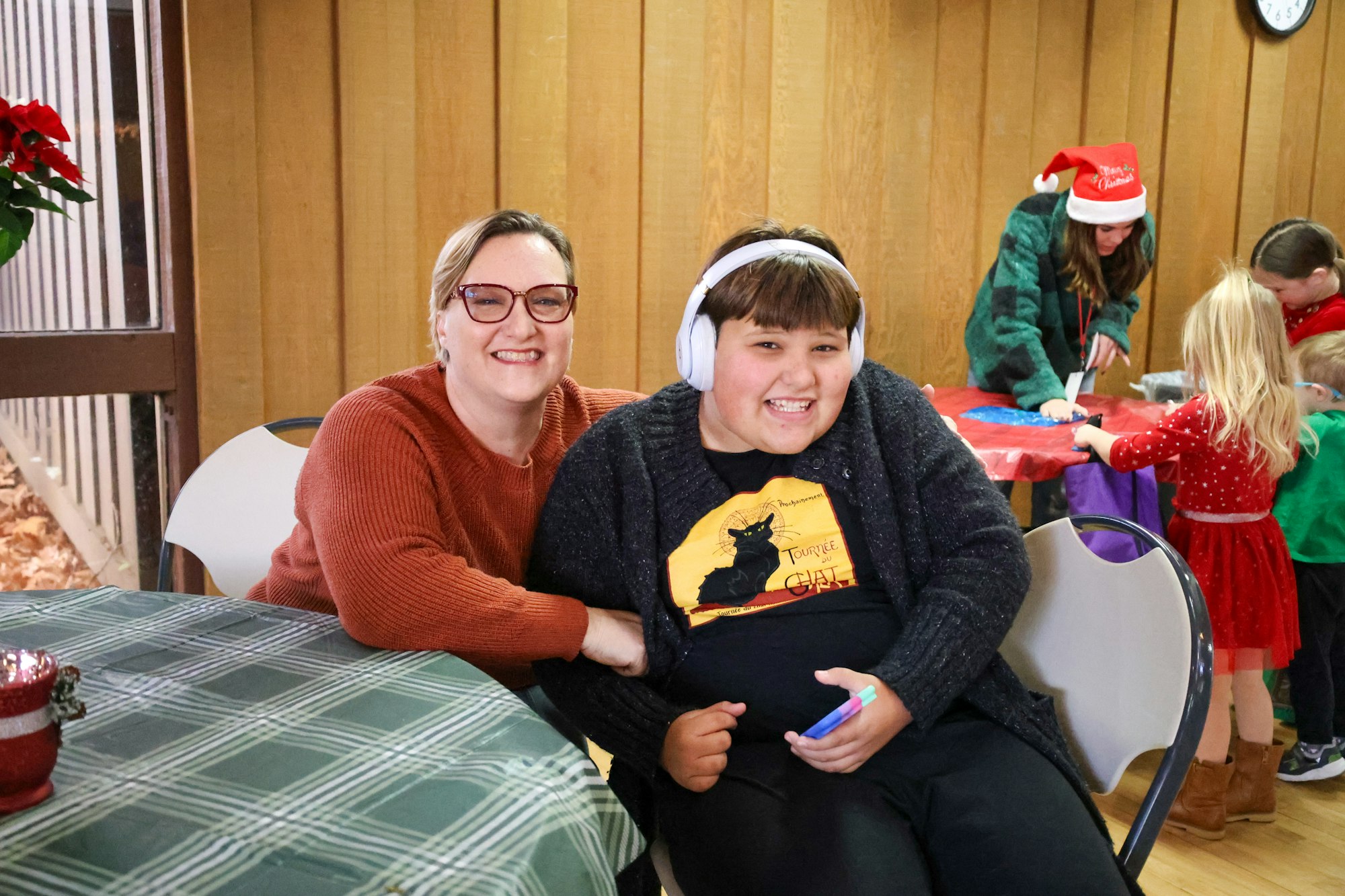 May contain: face, head, person, photography, portrait, electronics, headphones, accessories, glasses, clothing, footwear, shoe, people, chair, furniture, table, pen, child, female, girl, dining table, indoors, interior design, knitwear, sweater, couch, hat, restaurant, architecture, building, dining room, and room