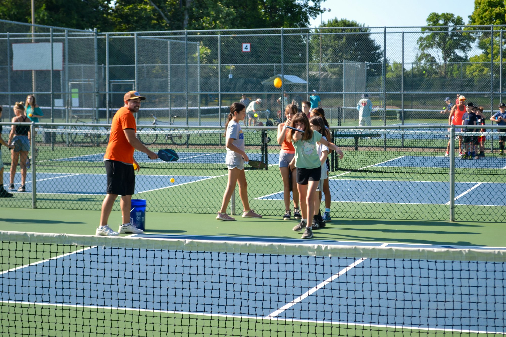 Tennis court with a coach and players during a lesson.