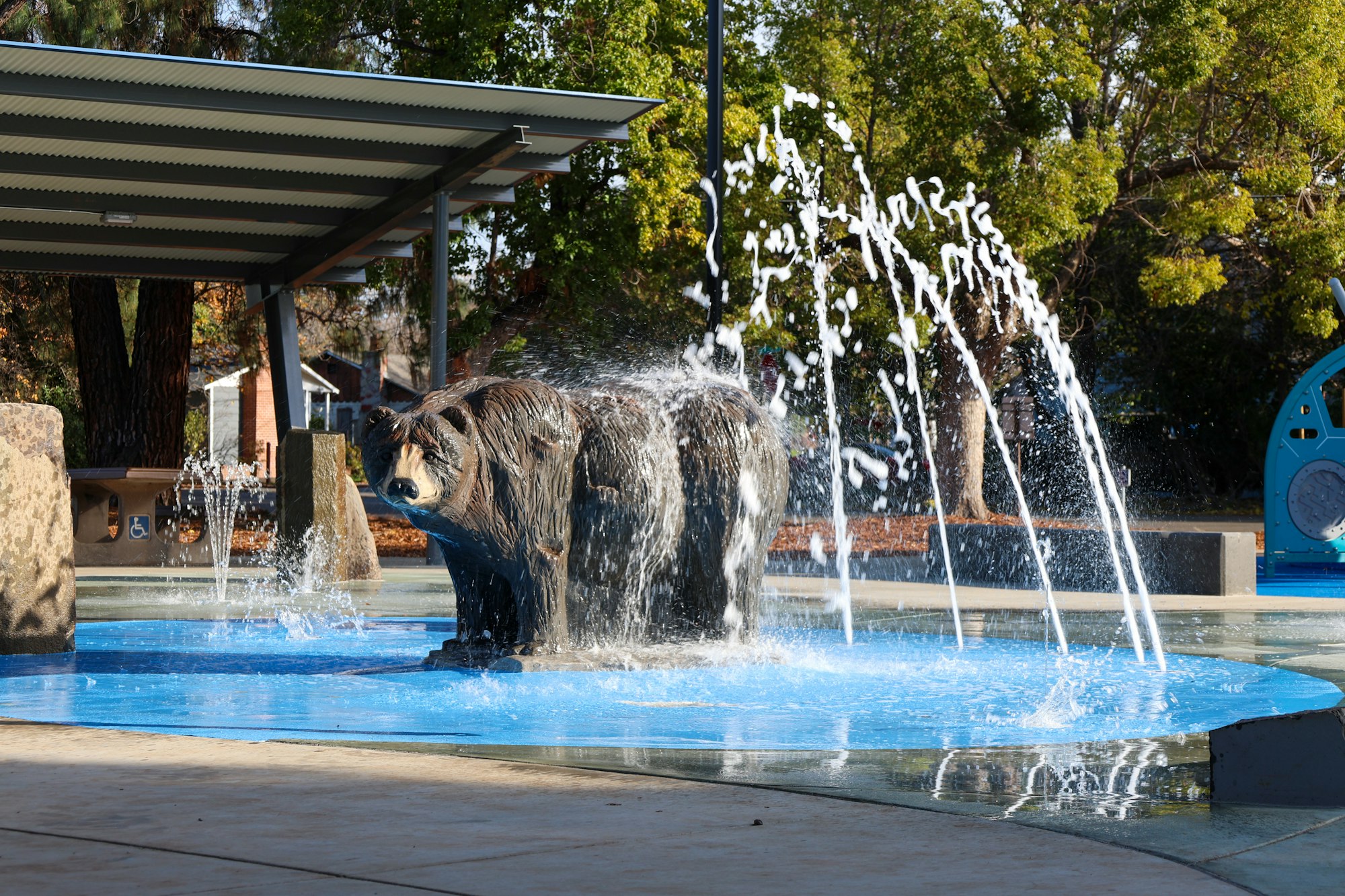 A bear statue in a fountain with water jets.