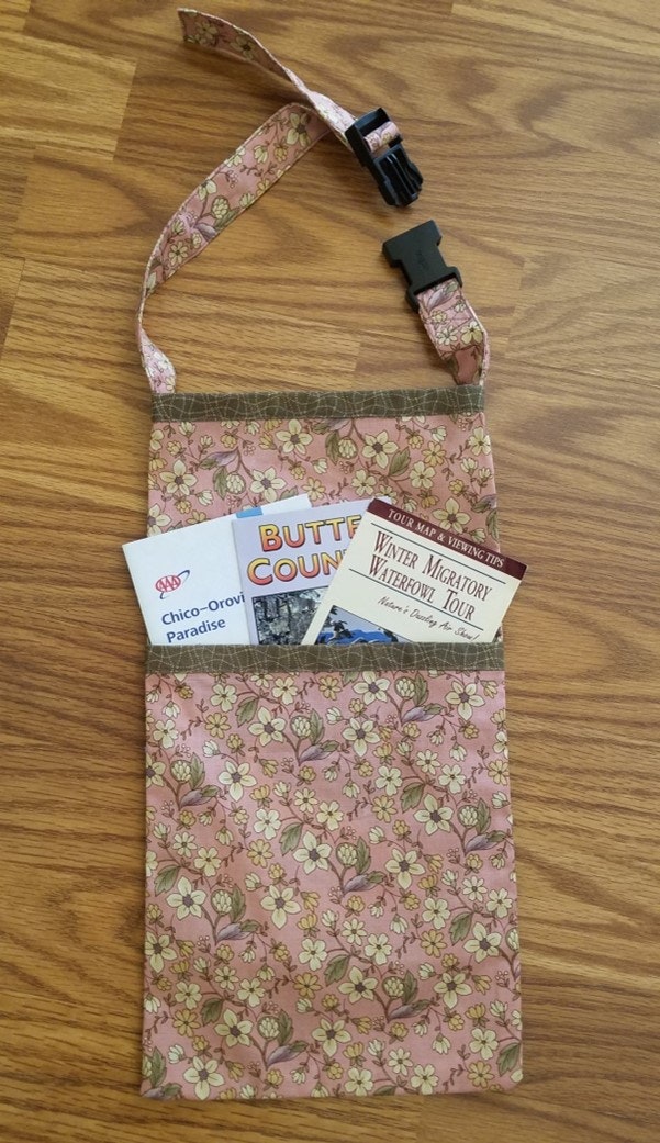 A floral fabric bag with a black buckle contains brochures for a county fair and migratory waterfowl tour.