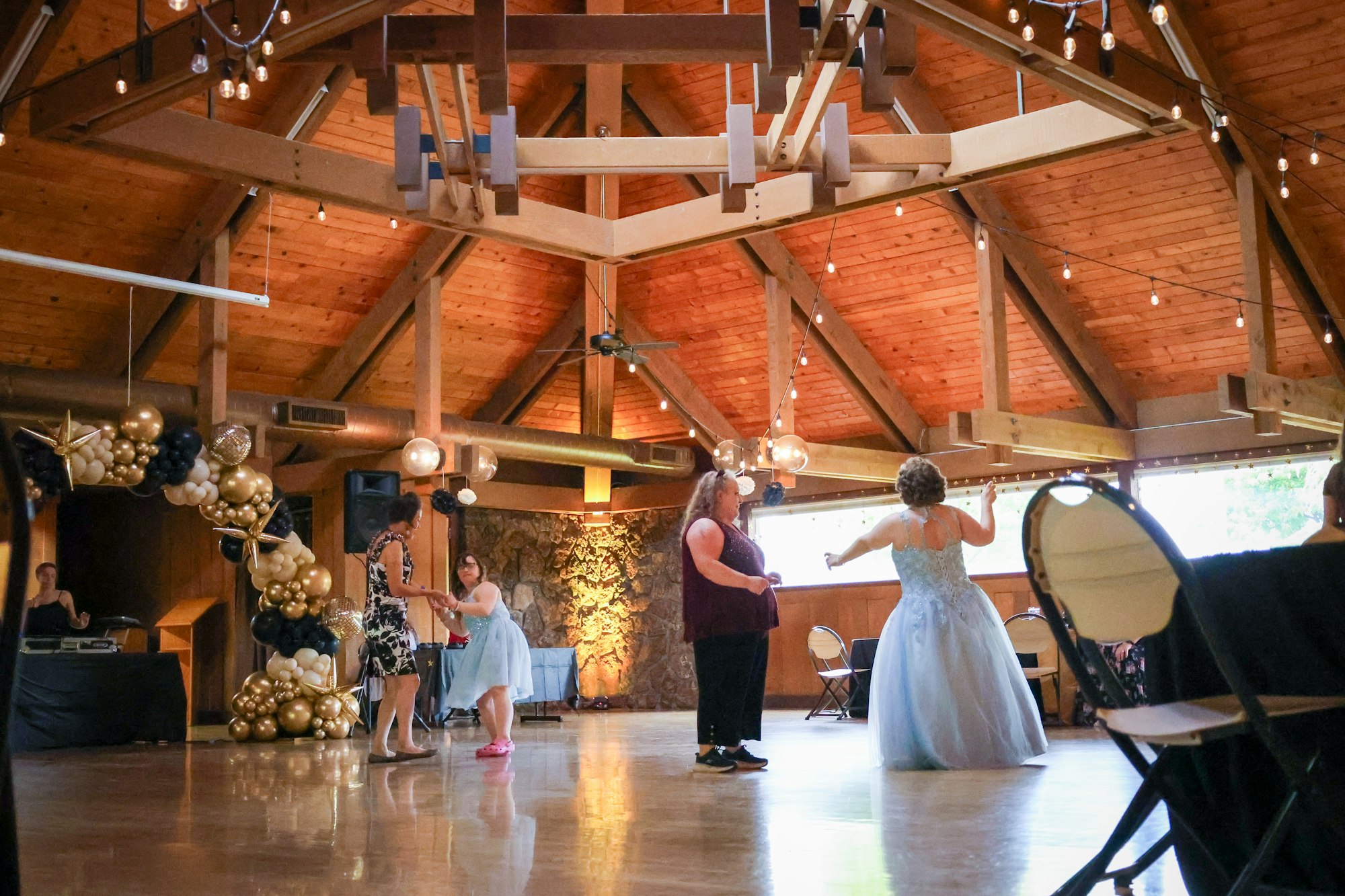 A festive indoor setting with women dancing, decorated with balloons, and warm lighting, creating a celebratory atmosphere.