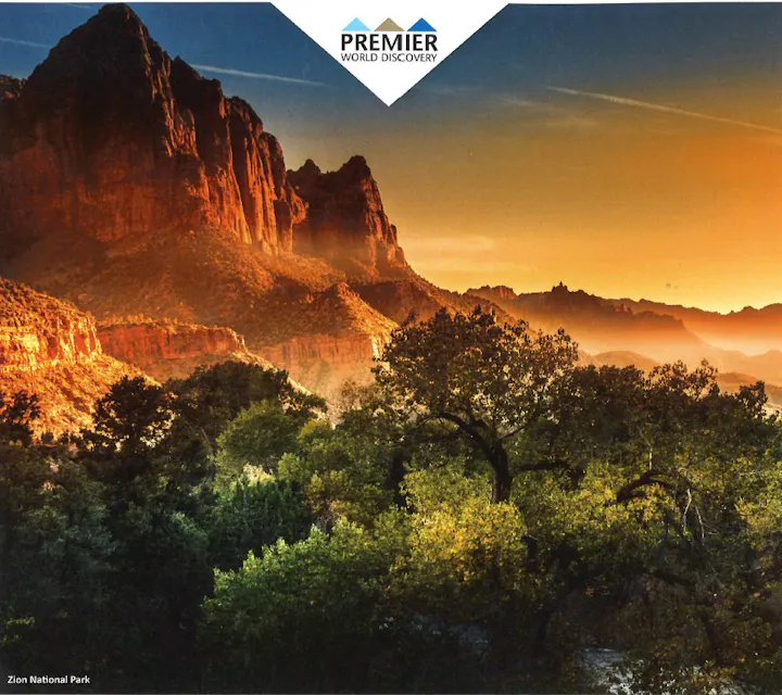 A stunning sunset over Zion National Park, showcasing towering cliffs and lush greenery, with branding for Premier World Discovery.