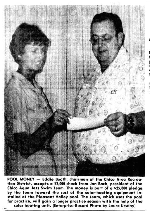 A man receives a check from a woman. The text mentions pool funding and solar heating equipment for a swim team.