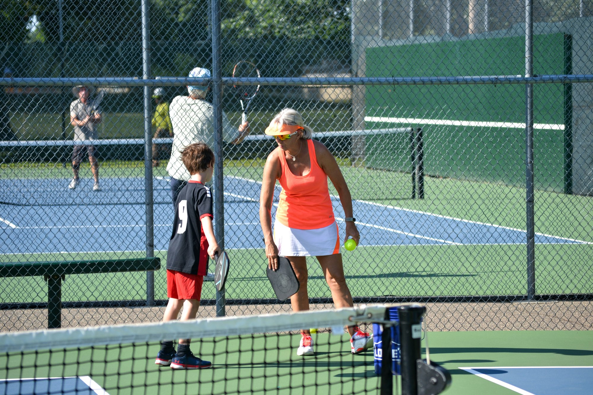 People playing pickleball and tennis on outdoor courts.