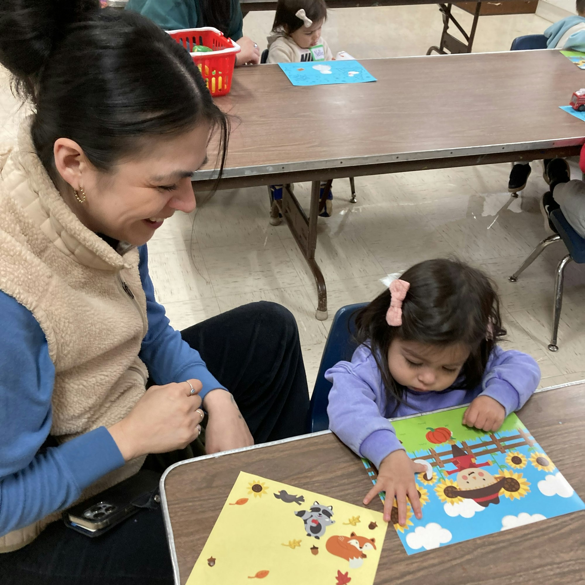 A woman and a child are seated at a table doing arts and crafts together.