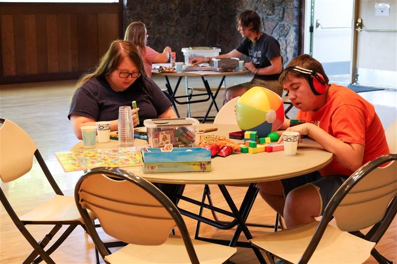 People sitting around a table with board games, snacks, and a beach ball.