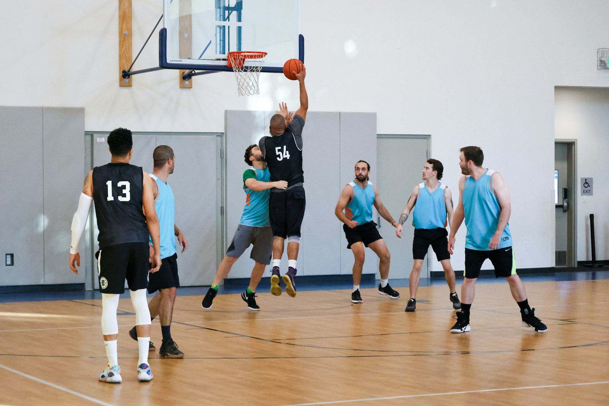A basketball game in progress with a player jumping for a layup.