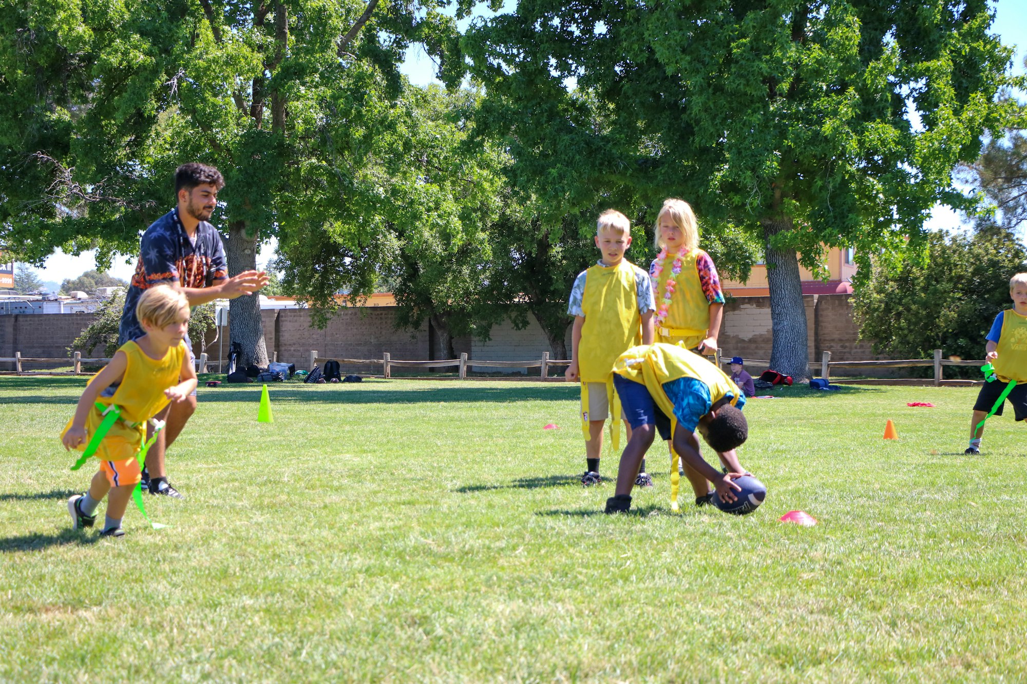 Kids playing a game in a park with an adult supervising.