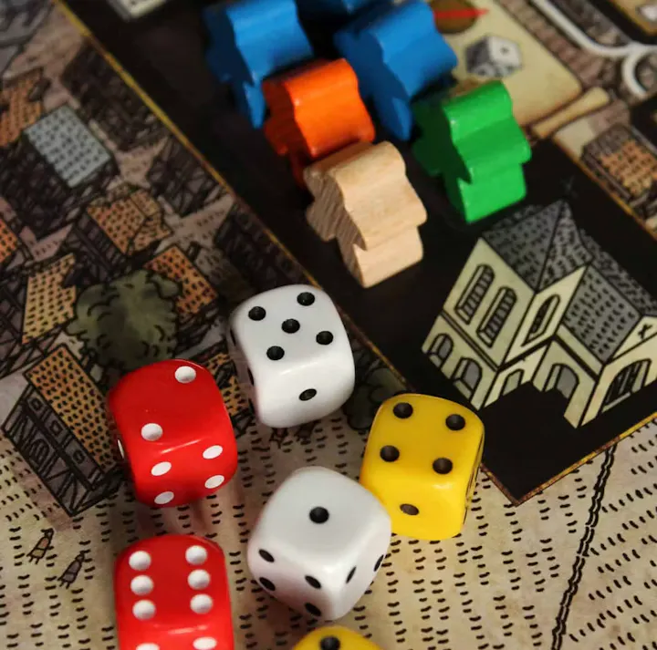 The image features a tabletop game setup with colorful game pieces and several dice on a detailed game board.