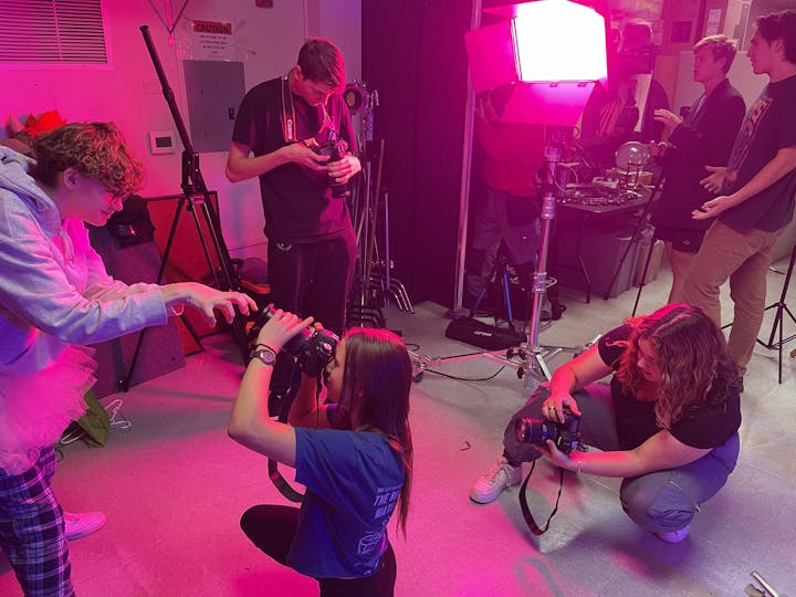 People with cameras in a studio setup, possibly doing a photography workshop or project.