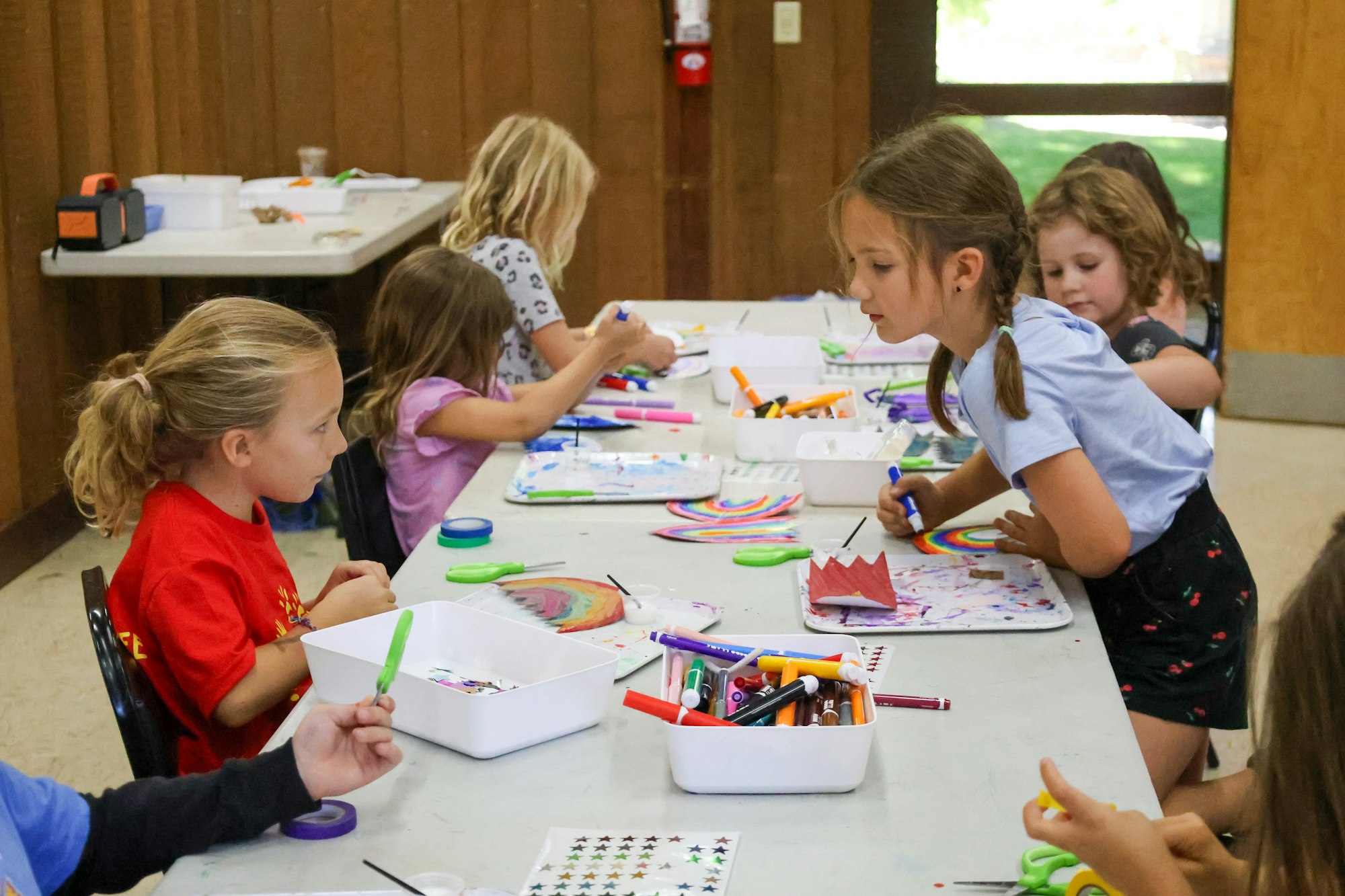 Children engaged in arts and crafts, colorfully drawing and creating on paper at a table.