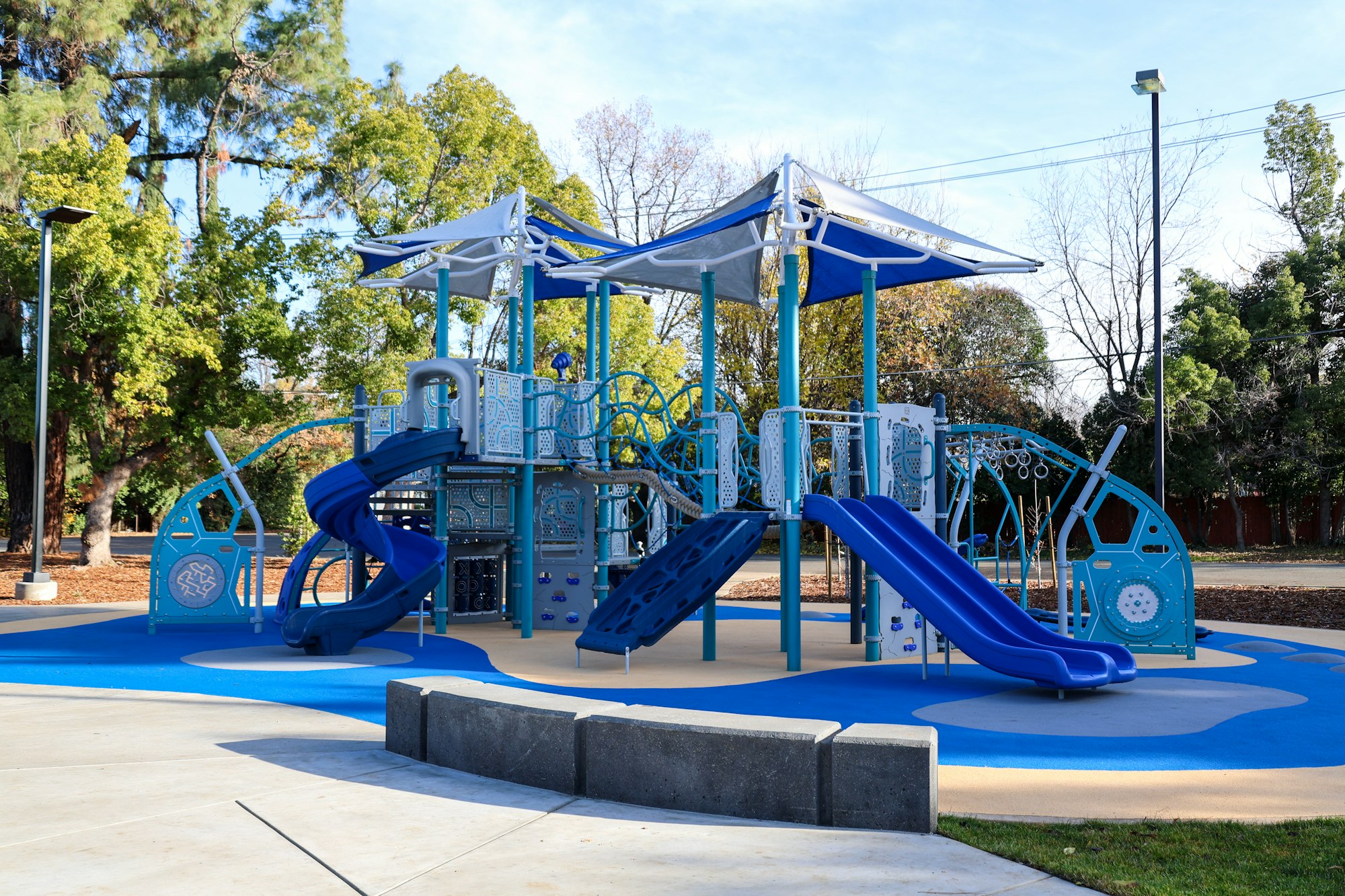 A colorful children's playground with slides and climbing structures on a sunny day.