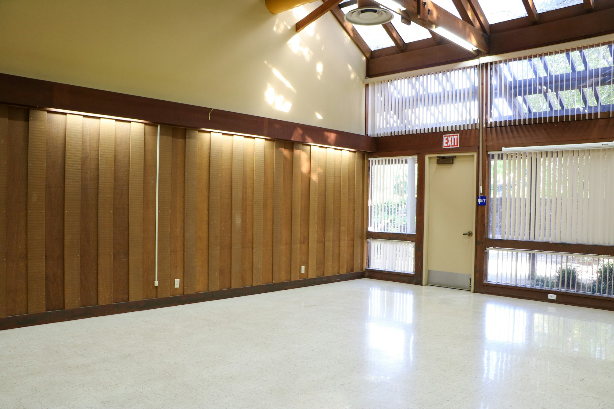 Empty room with wooden blinds, tiled floor, and a skylight.
