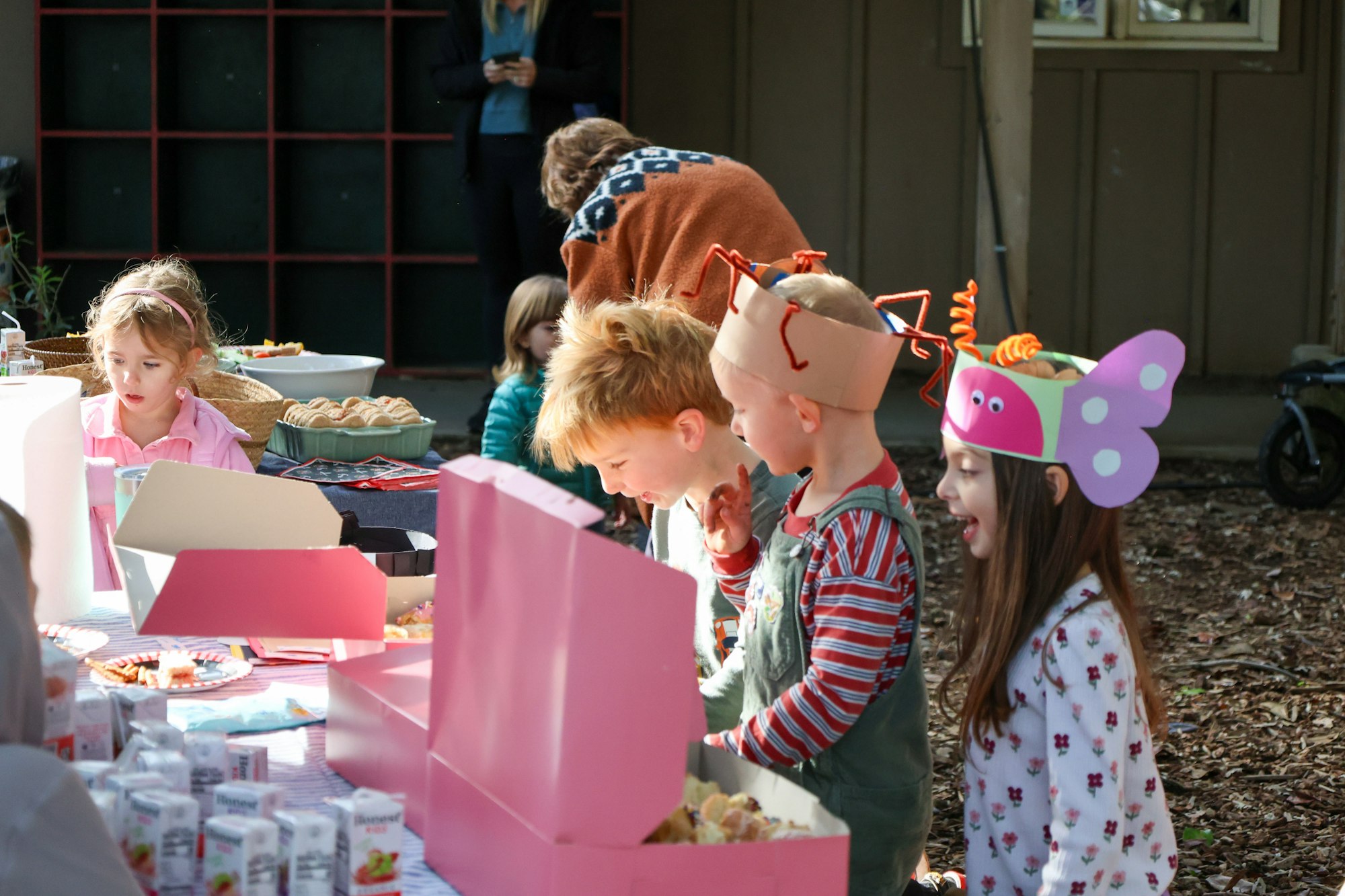 A gathering of children at a festive table with snacks and colorful hats, enjoying a fun atmosphere while exploring treats.