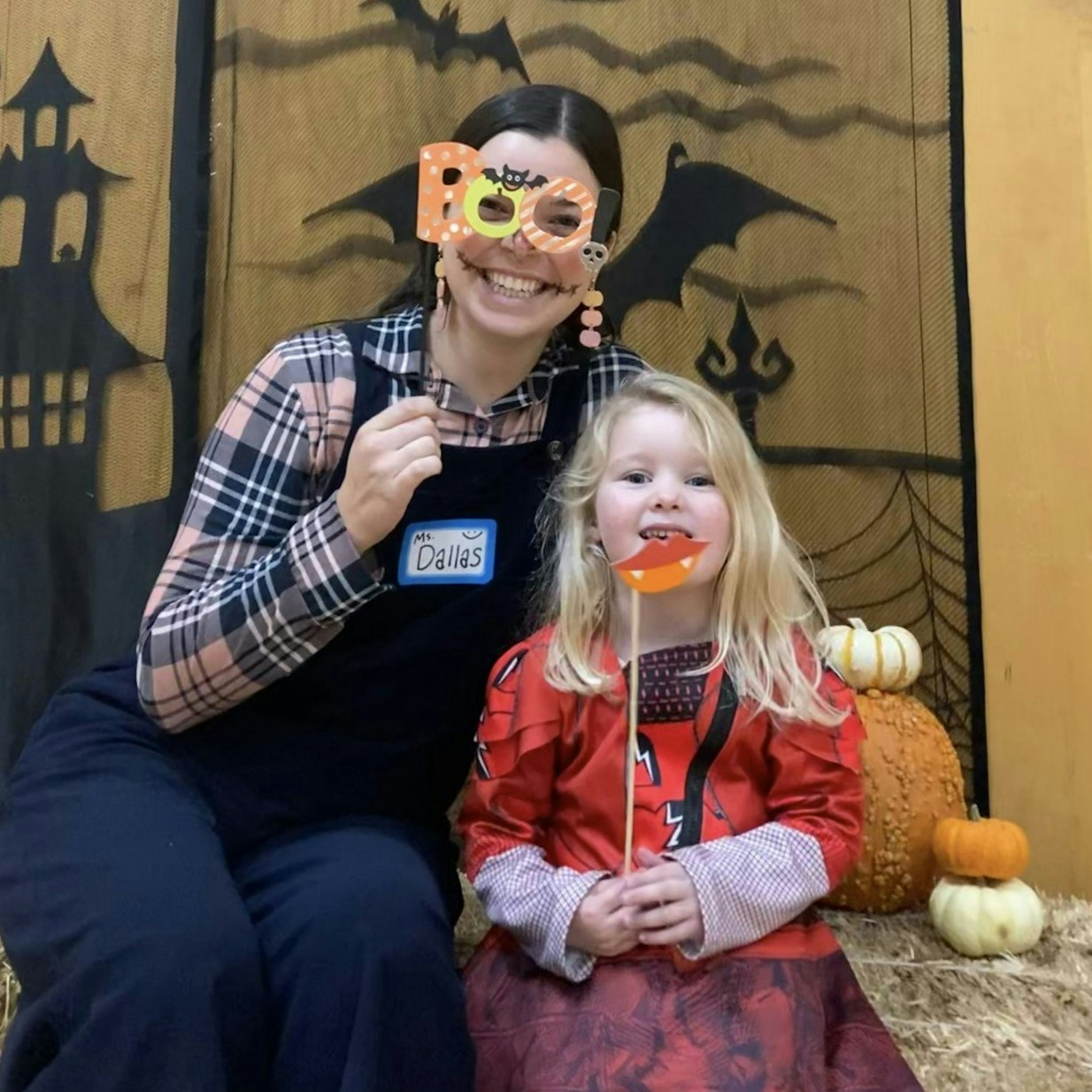 Two people posing with Halloween props, surrounded by pumpkins and festive decorations.