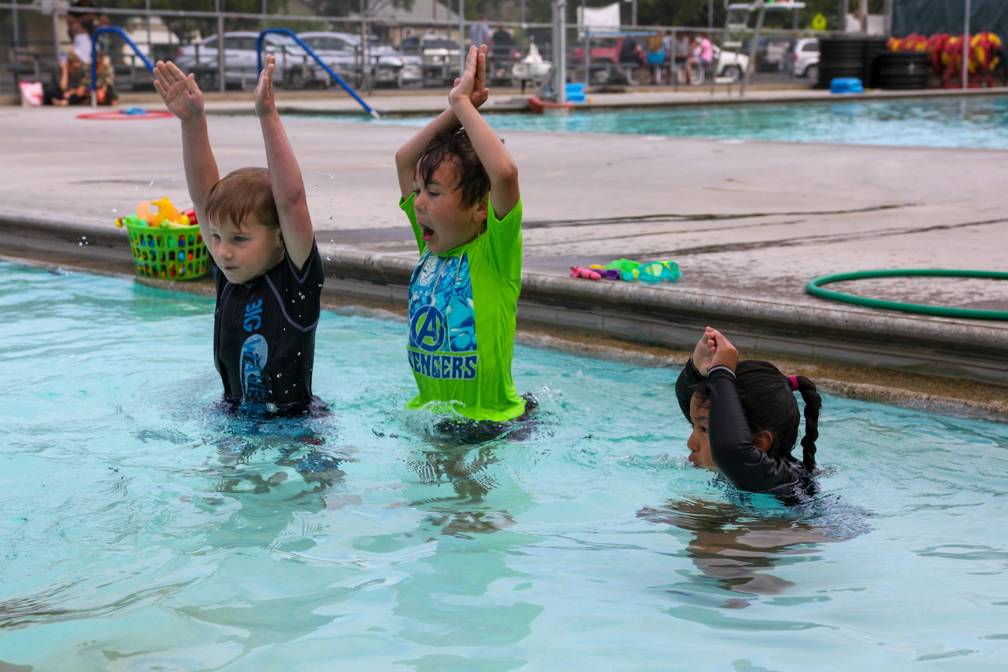 Three kids having fun while learning to swim in a pool.