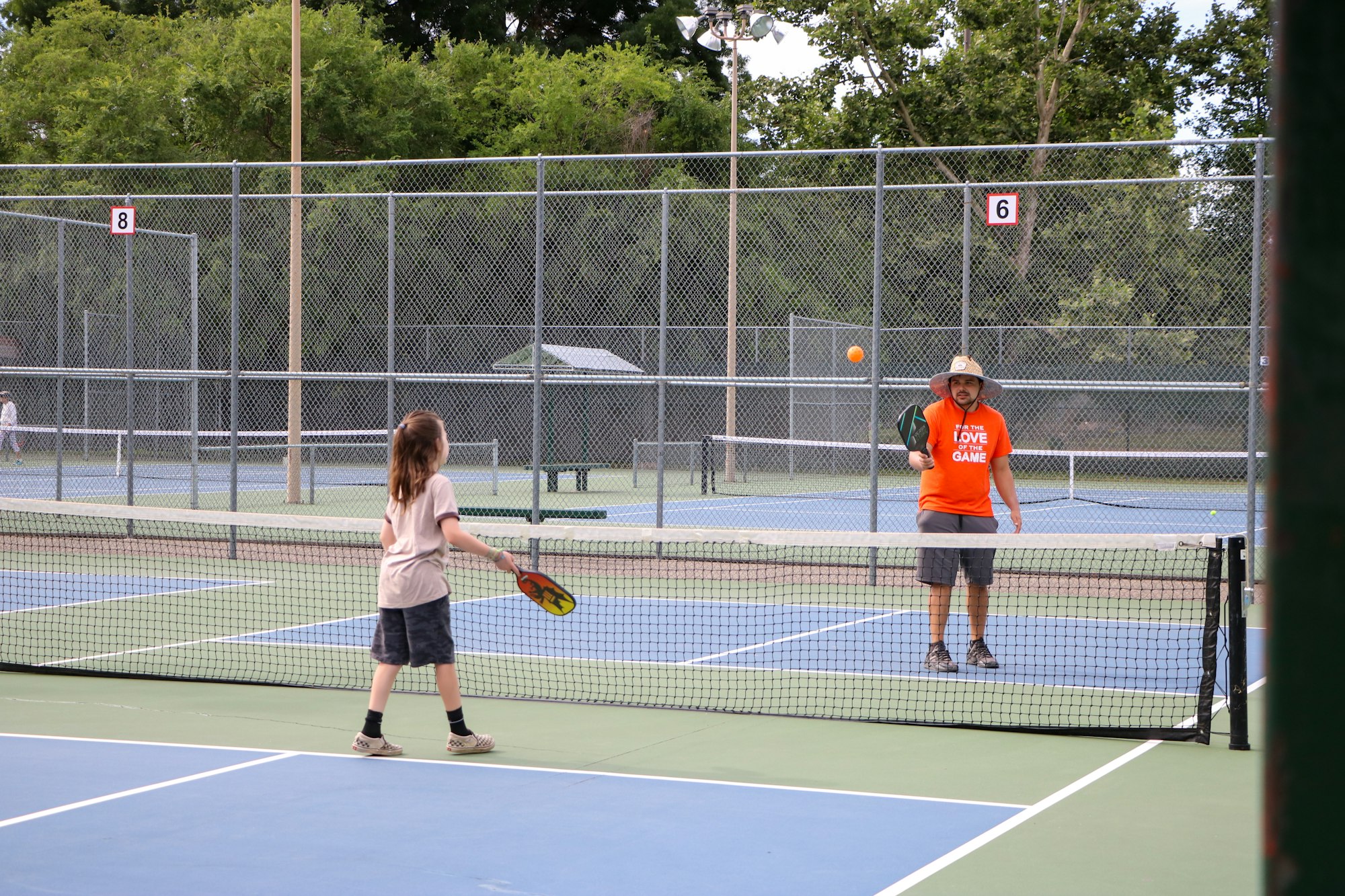 Two people playing pickleball on an outdoor court.